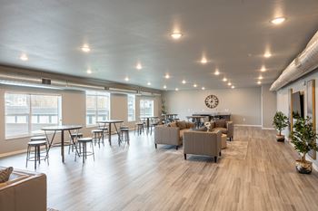 An open living room with couches and tables and a clock on the wall